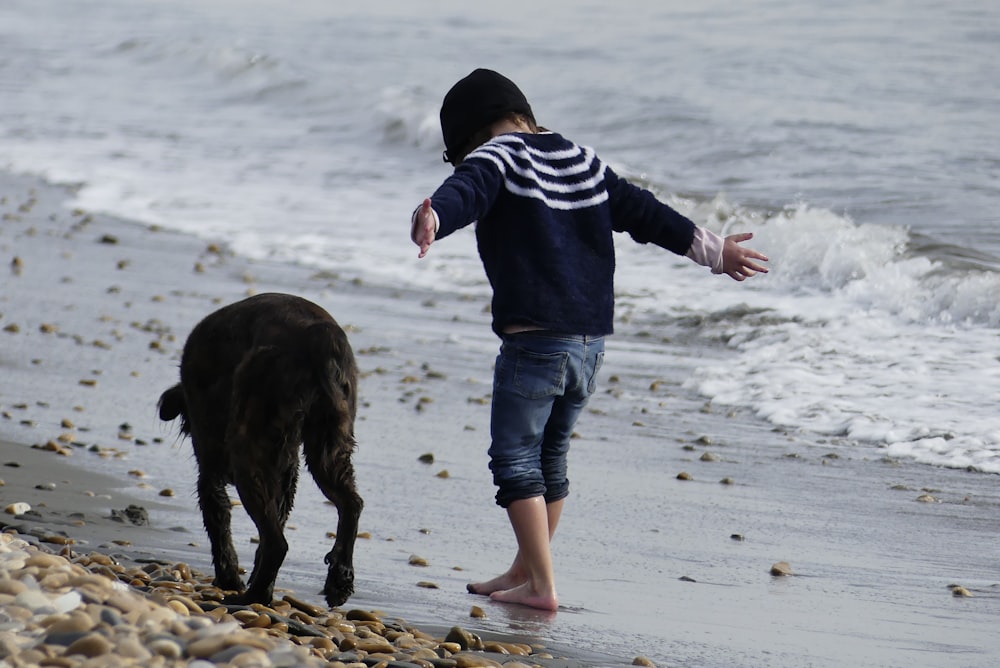 a child and a dog playing on the beach