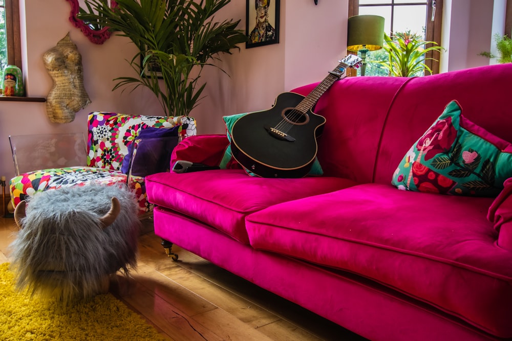 uma sala de estar com um sofá rosa e uma guitarra