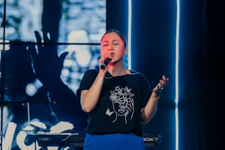 a woman singing into a microphone on stage