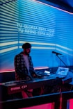 a man sitting at a keyboard in front of a microphone