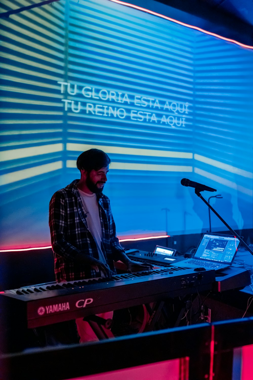 a man sitting at a keyboard in front of a microphone