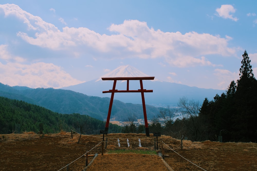 a wooden structure in the middle of a field with mountains in the background