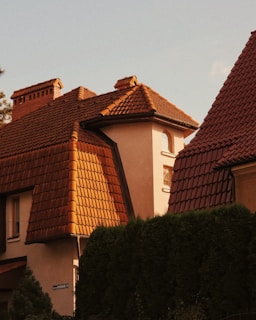 Wide shot of a traditional house showcasing a newly completed red tile roof under a bright sky.