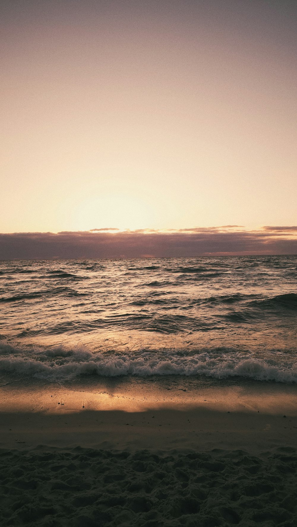 the sun is setting over the ocean on the beach