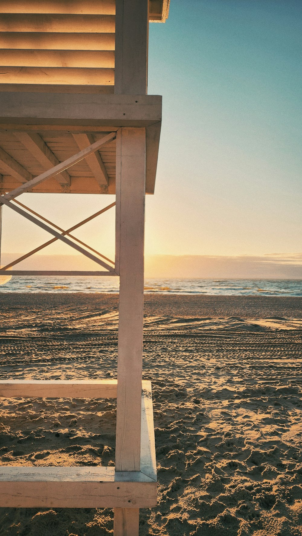 a lifeguard tower on a beach at sunset