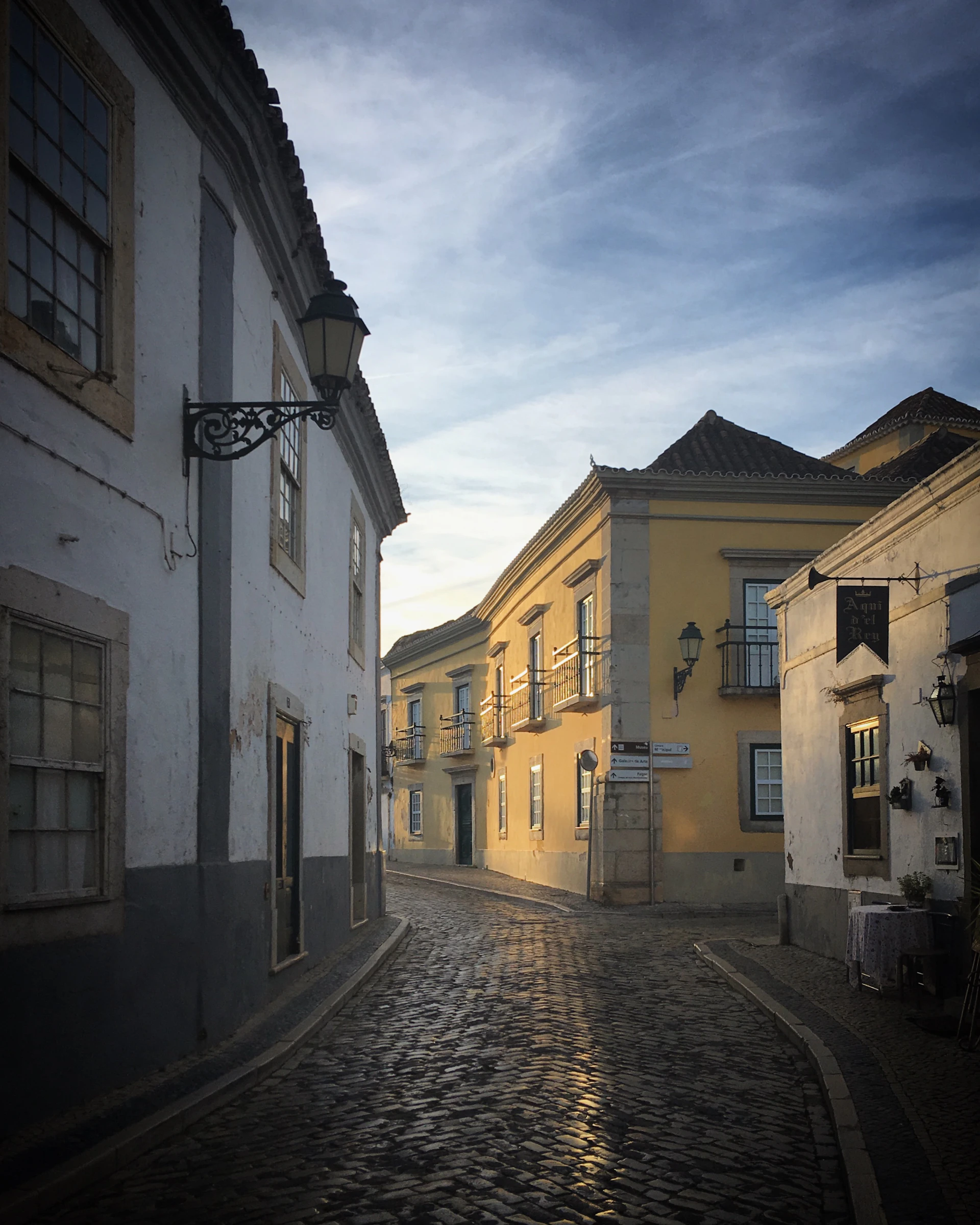 A charming old street in the region with vintage houses and cobblestone pavement under a warm sunset.