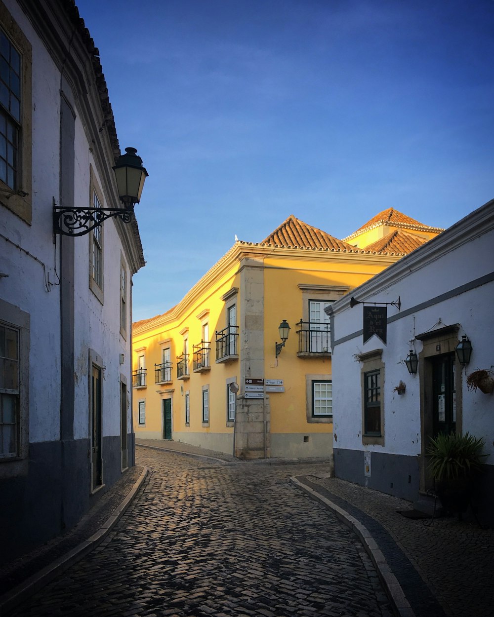 a cobblestone street with a yellow building in the background