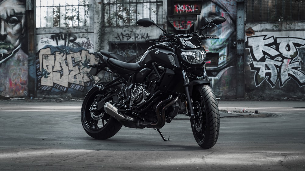 a black motorcycle parked in front of a graffiti covered wall