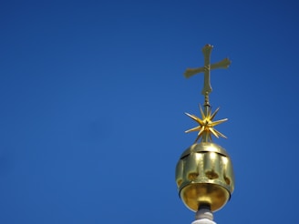 An elegant golden cross shining against a deep blue sky, evoking faith and divine guidance