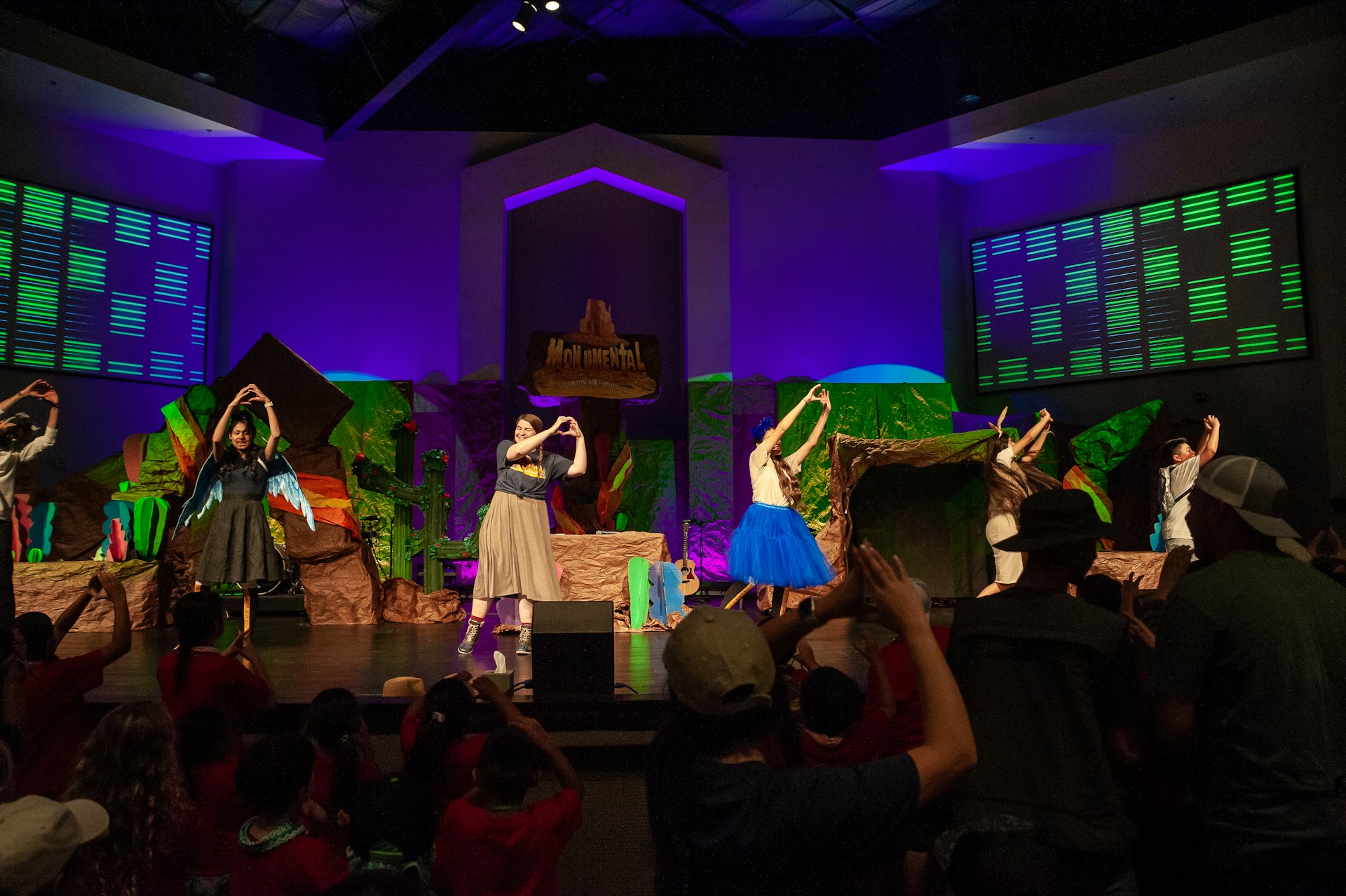 A vibrant dance troupe mid-leap under dramatic stage lighting, capturing the energy and precision of a live performance.