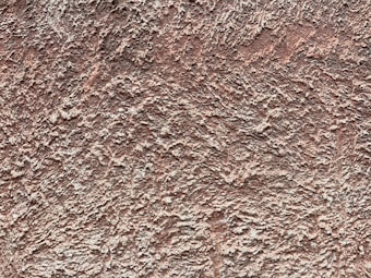 A textured surface with a rough, uneven pattern resembling a stucco or plaster wall. The texture is made up of many small ridges and crevices, giving it an organic and natural appearance.