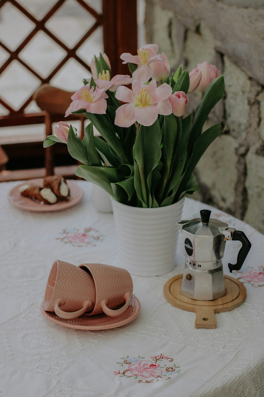 a table topped with pink flowers next to a cup of coffee