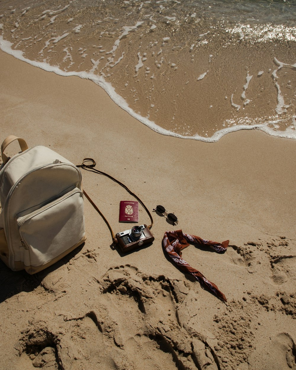 a backpack and other items lay on the sand of a beach