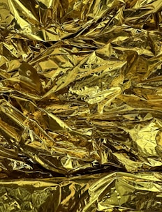 Shiny aluminum foil paper sheets reflecting royal gold hues, displayed in a bakery setting.
