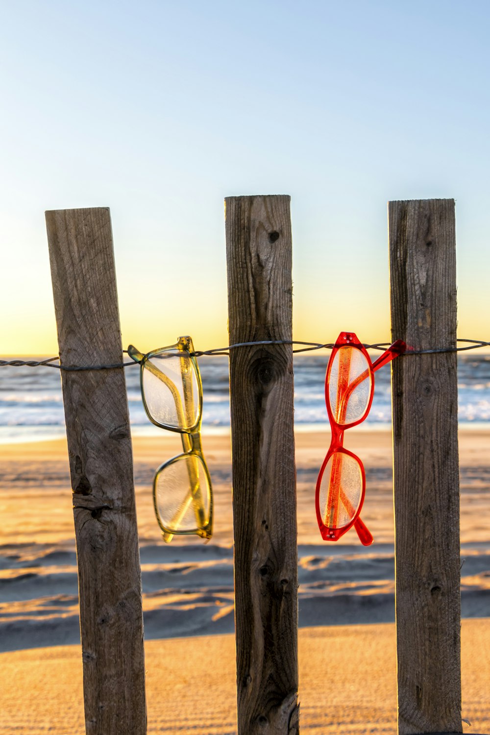 a pair of red glasses hanging on a wooden fence