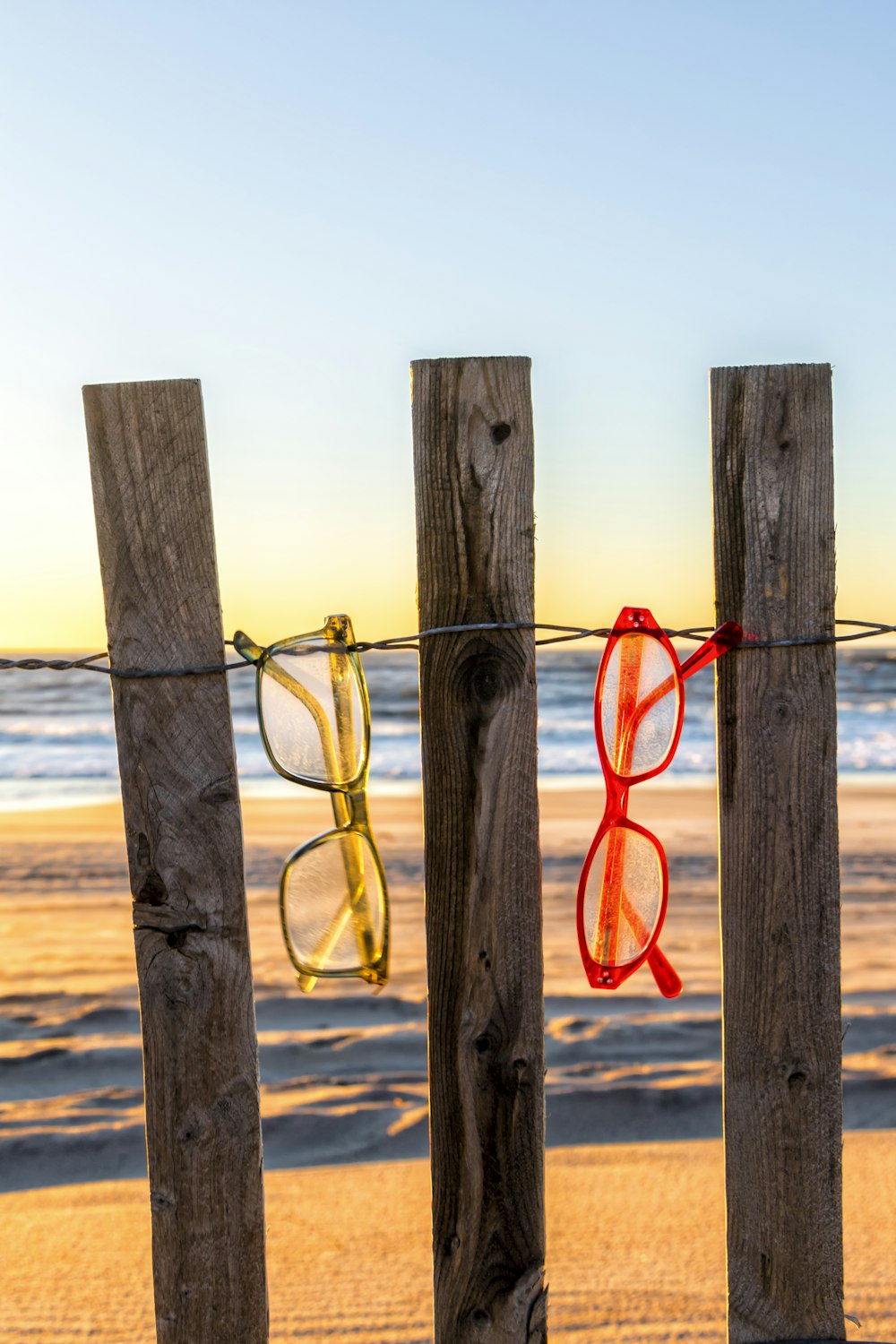 Un par de gafas rojas colgadas de una valla de madera