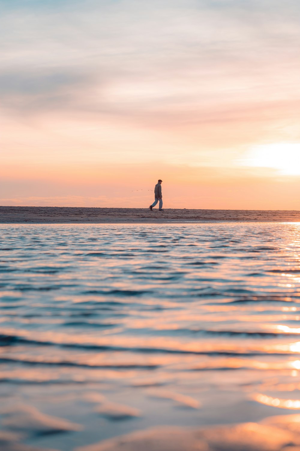 a man standing on a surfboard in the ocean at sunset