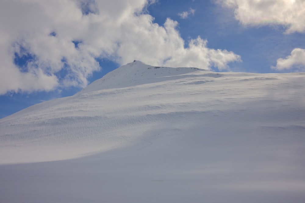 a snow covered mountain under a cloudy blue sky