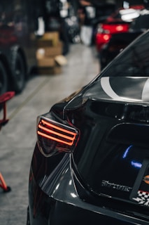 Close-up of a high-quality car subwoofer with illuminated red details in a dark garage setting.