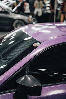A close-up of polished car details reflecting the ambient glow of a bustling event venue