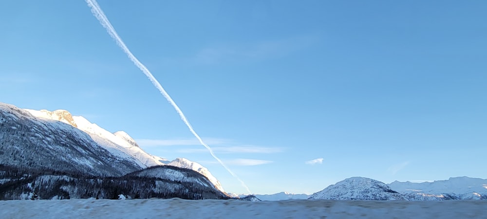 a view of a mountain with a contrail in the sky