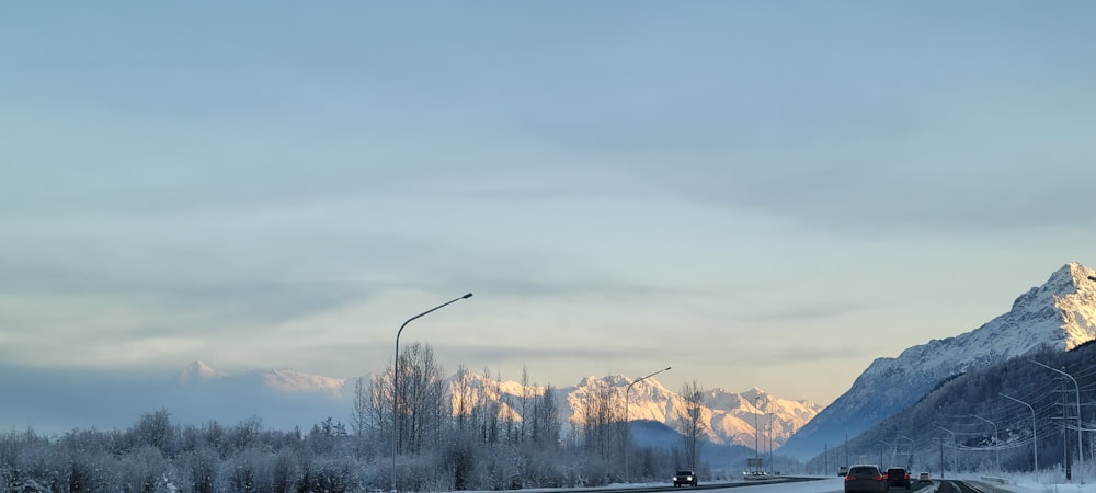 a snowy road with mountains in the background