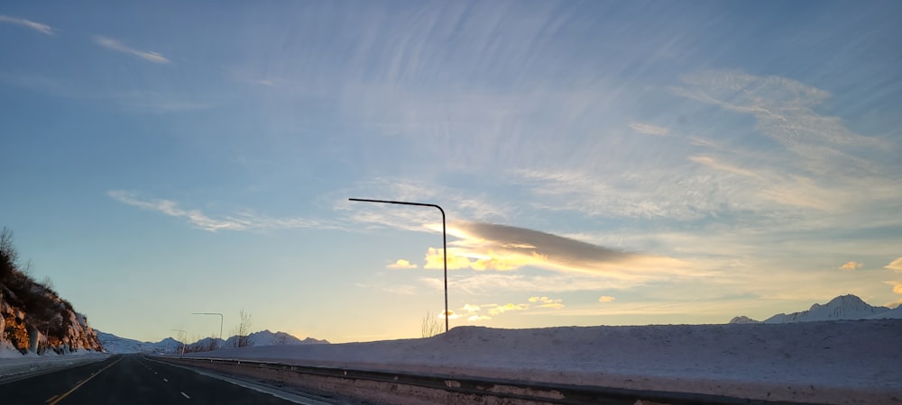 the sun is setting on a snowy road