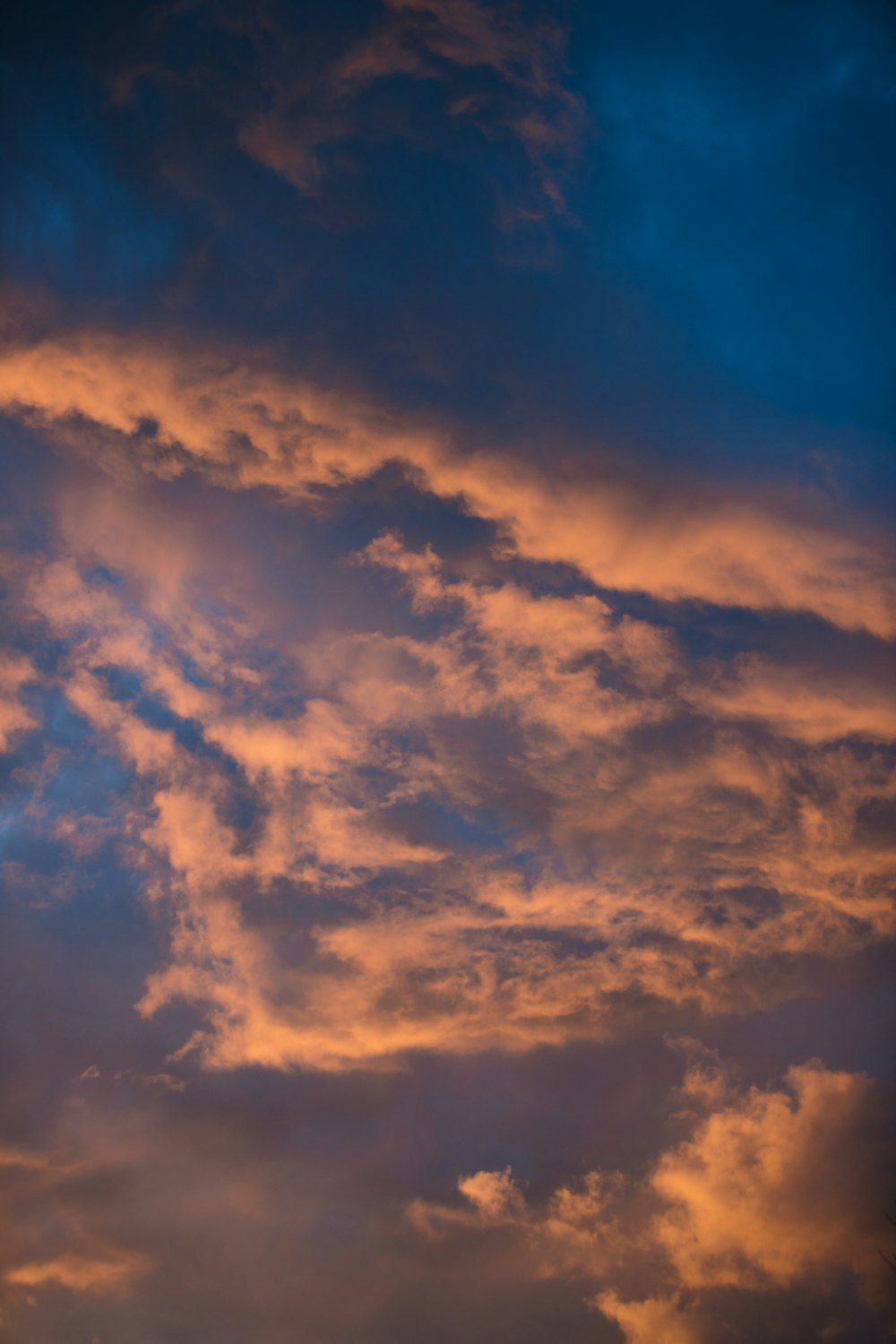 a plane flying through a cloudy sky at sunset