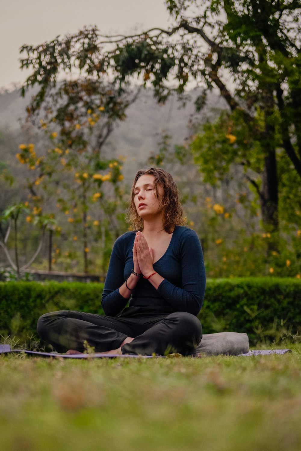 a woman sitting in a yoga position in a park