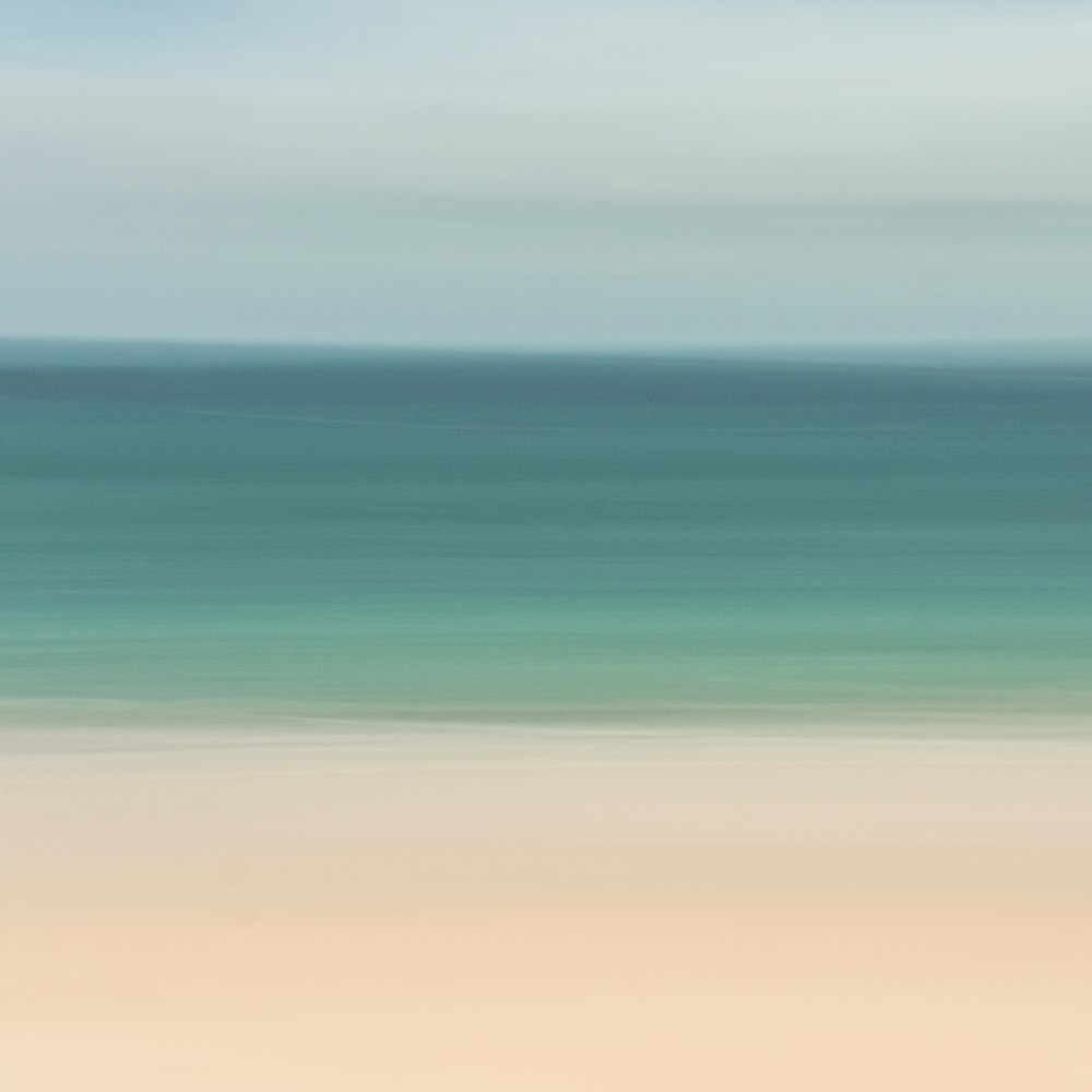 A blurry photo of a beach with a blue ocean in the background ...