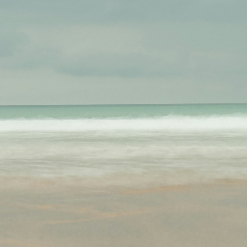 a person walking on the beach carrying a surfboard