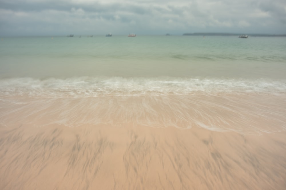 a blurry photo of a beach with boats in the water
