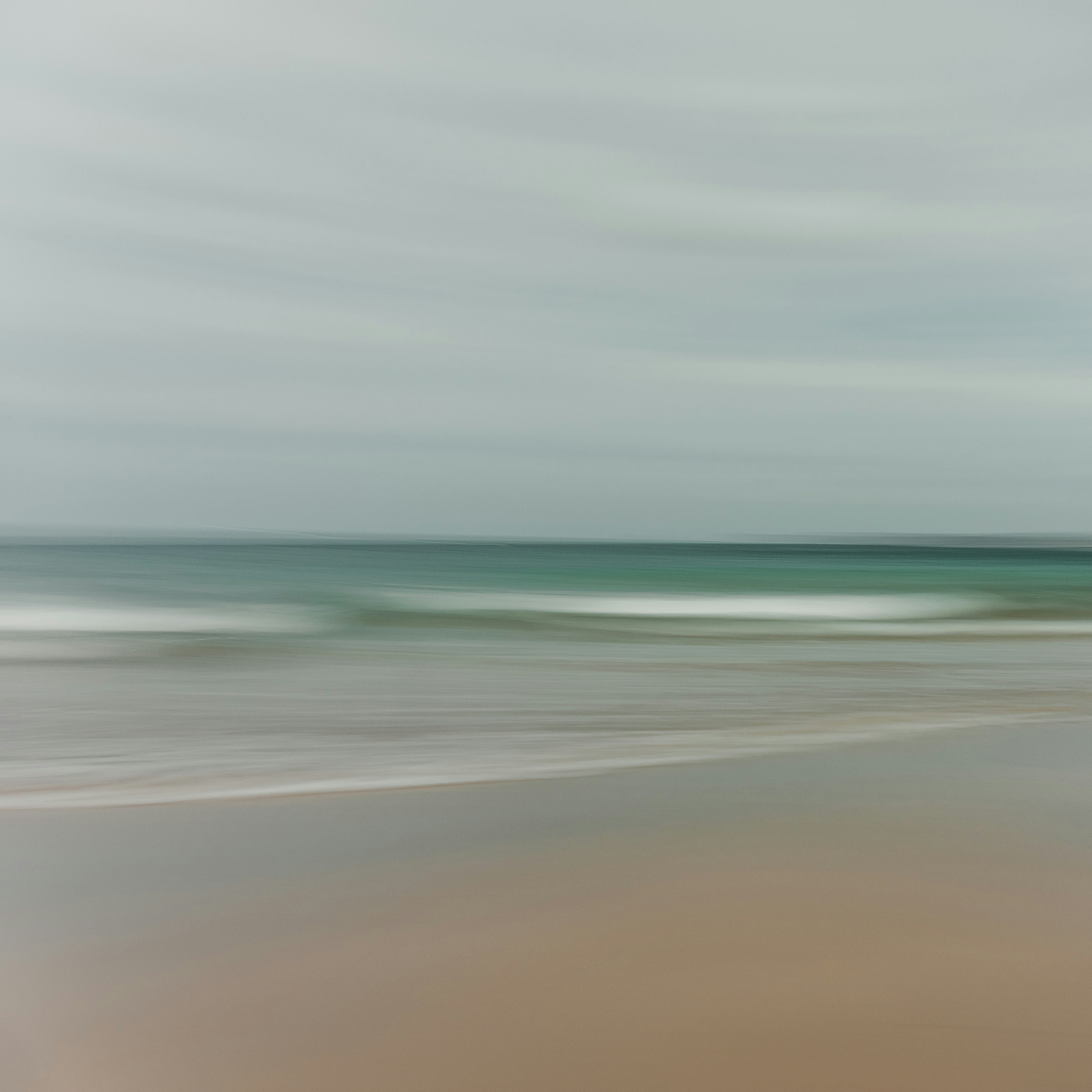 une photo floue d’une plage avec une vague qui arrive