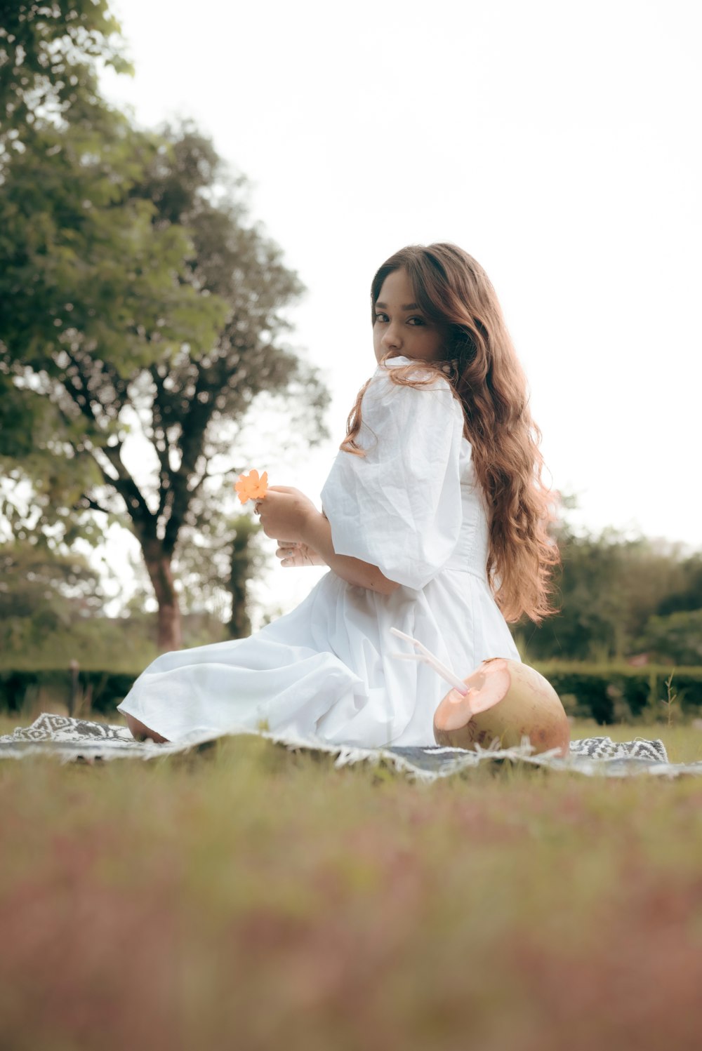 a girl in a white dress sitting in a field