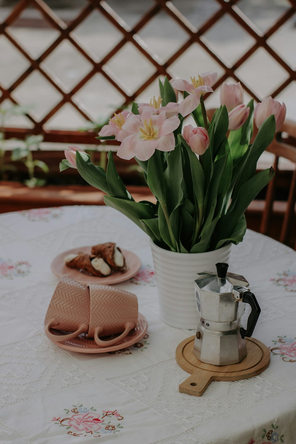 a table topped with a white vase filled with pink flowers