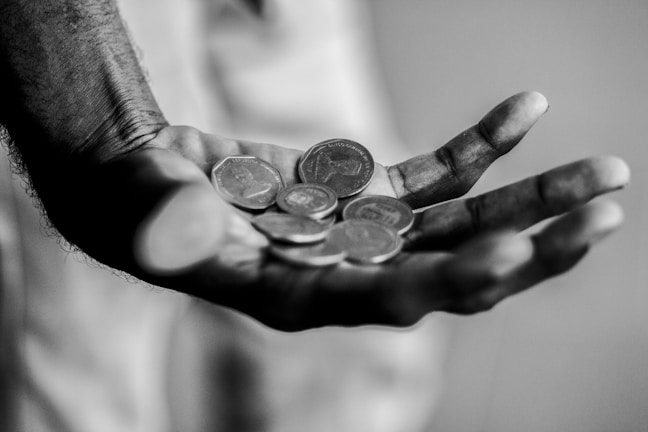 A close-up of hands counting coins on a wooden table.