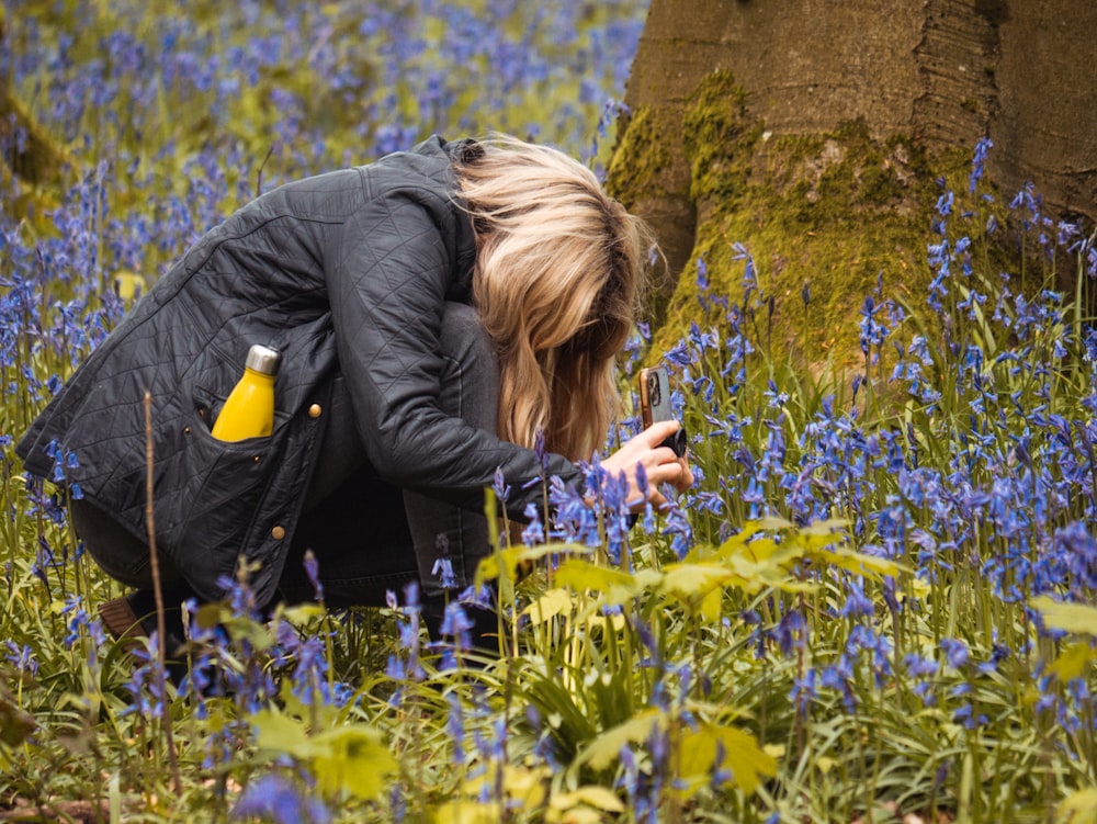 Une femme agenouillée dans un champ de fleurs bleues