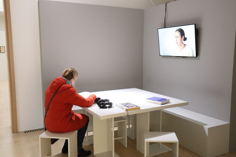 a person sitting at a table in front of a tv