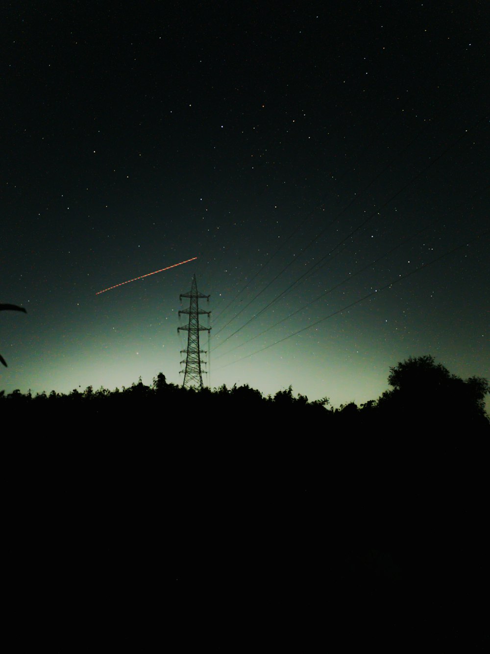 a power line at night with the moon in the sky