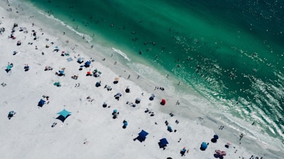 Aerial view of a vibrant beach with colorful umbrellas and clear blue water.