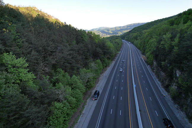Aerial view of a newly constructed multi-lane highway cutting through green terrain.