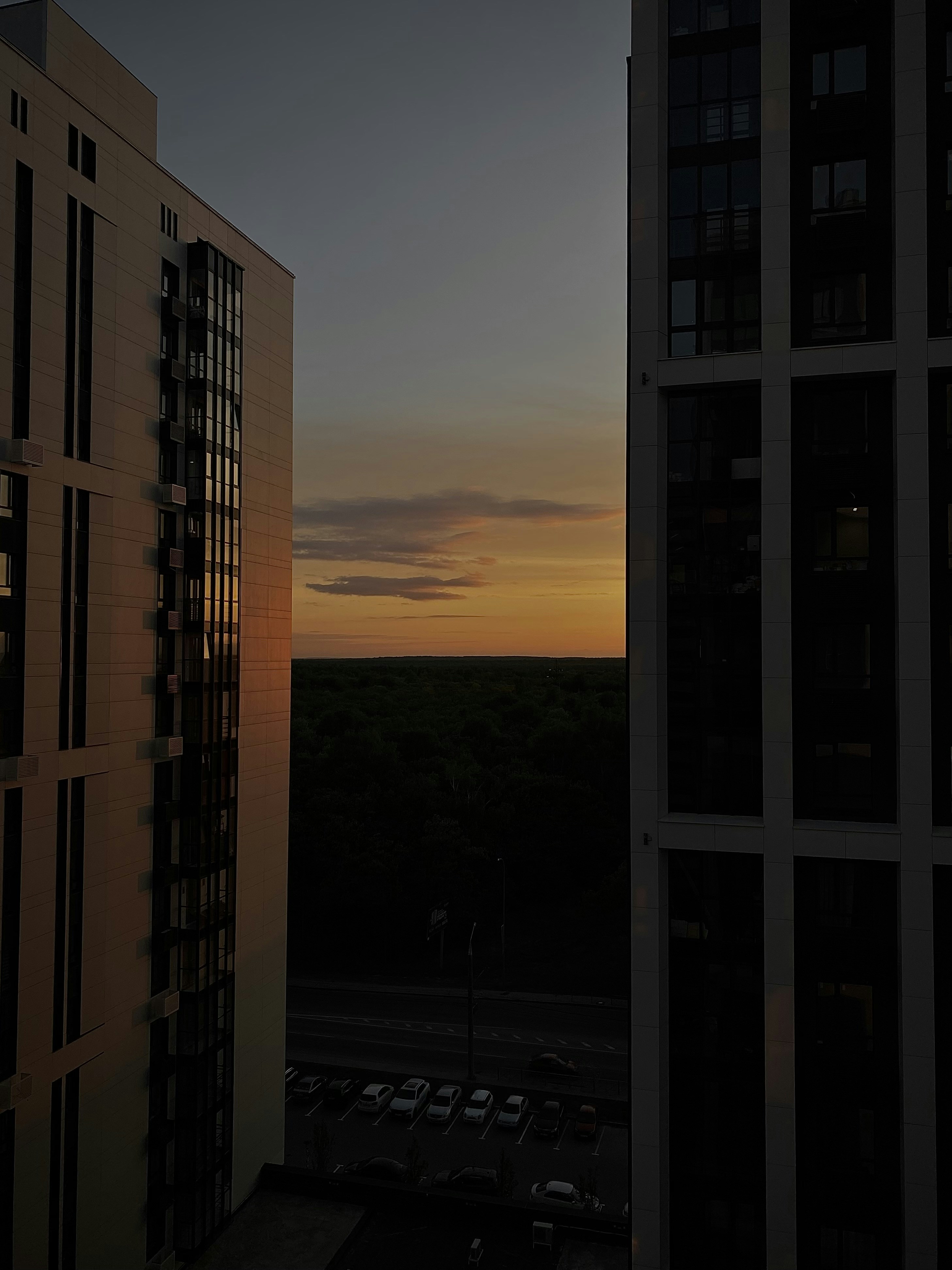 the sun is setting over a city with tall buildings