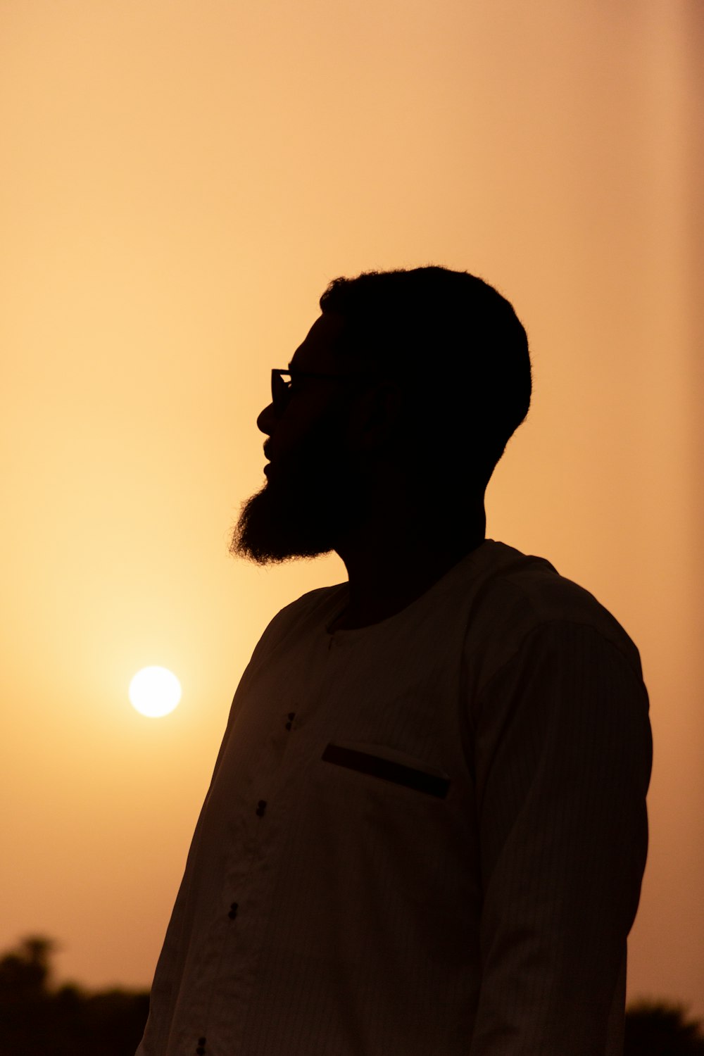 a man with a beard standing in front of the sun