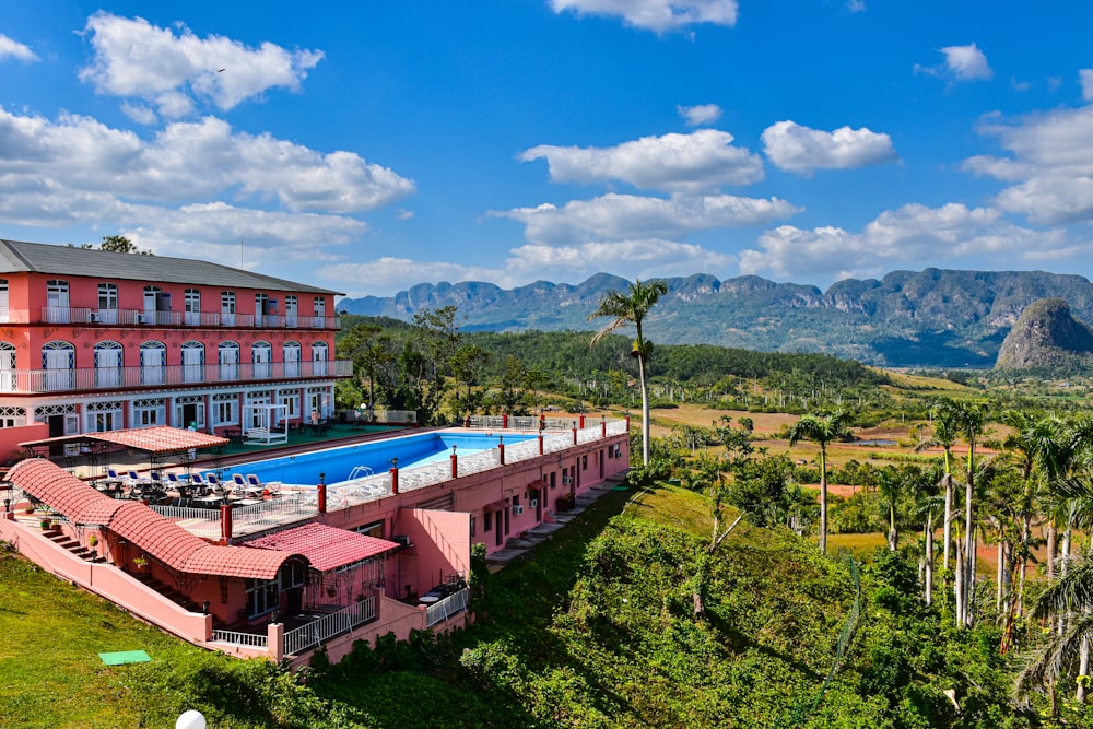 an aerial view of a hotel with a pool and mountains in the background