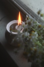 A lit candle sitting on top of a window sill