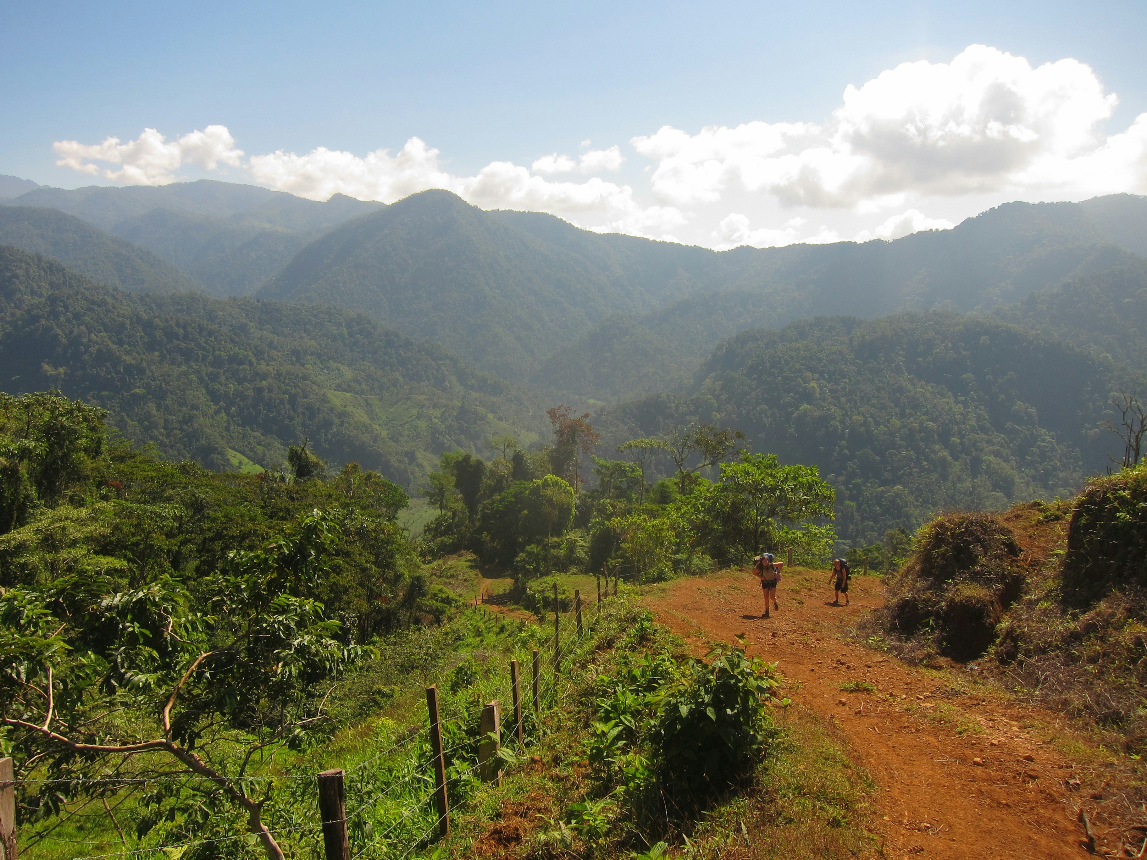 a person walking down a dirt road in the mountains, 