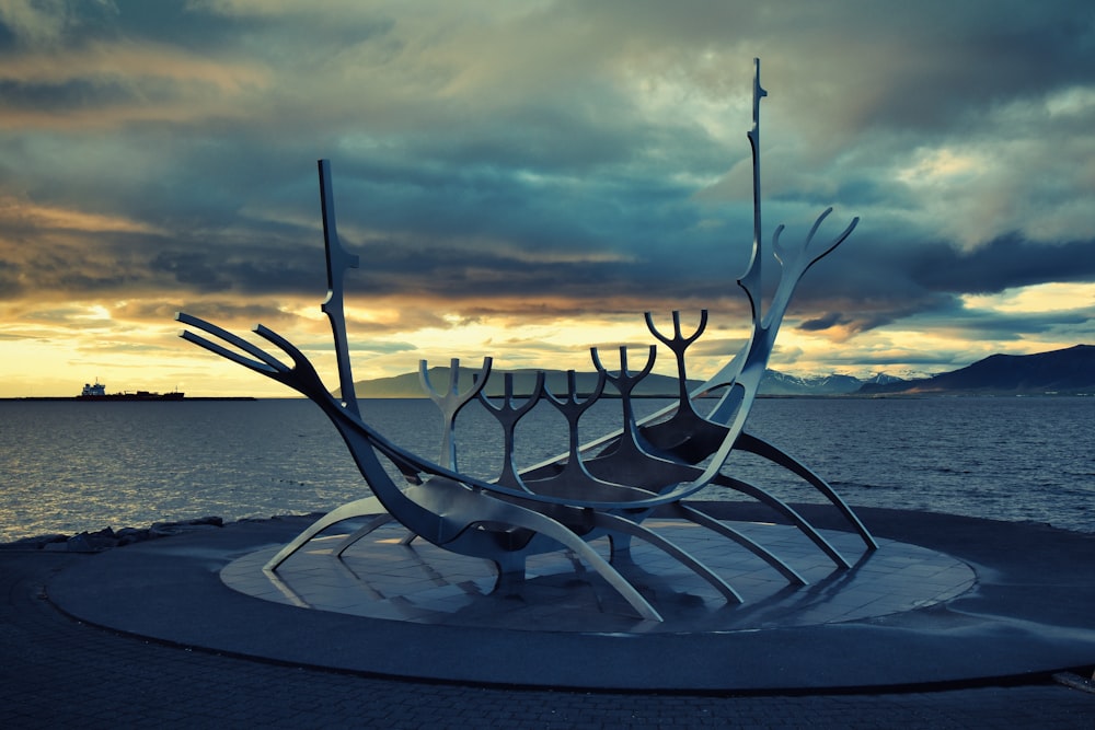 a large metal sculpture sitting in front of a body of water