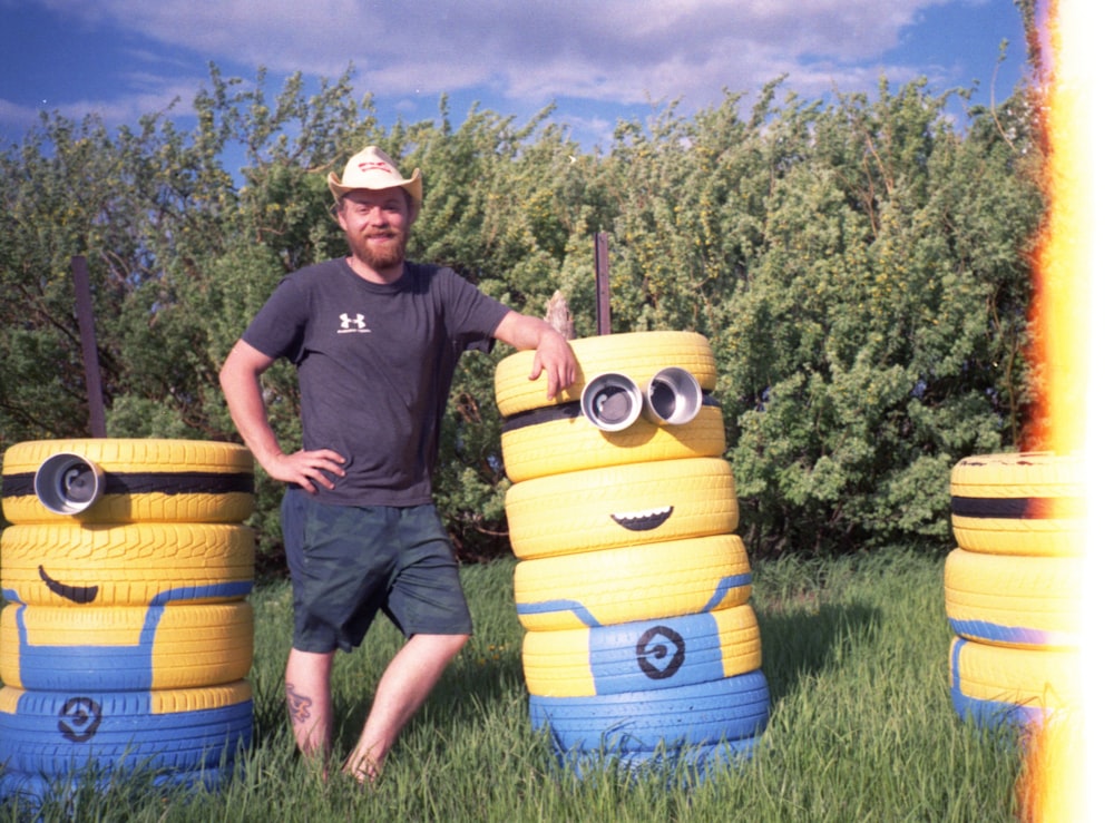 a man standing next to a stack of yellow and blue tires