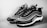 A pair of stylish sneakers with a modern design featuring a black and white color scheme. The shoes have a wave-like pattern on the sides, detailed lacing, and a sleek silhouette. The background is plain, emphasizing the footwear.