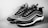 A pair of stylish sneakers with a modern design featuring a black and white color scheme. The shoes have a wave-like pattern on the sides, detailed lacing, and a sleek silhouette. The background is plain, emphasizing the footwear.